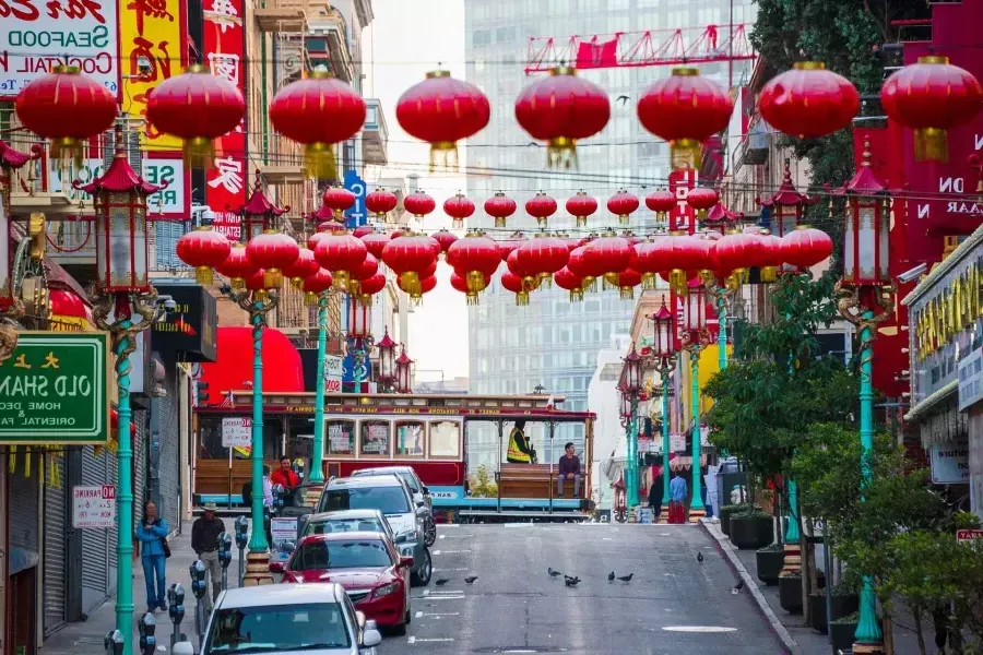 Se muestra una calle montañosa en el barrio chino de 贝博体彩app con faroles rojos colgando y un tranvía pasando.